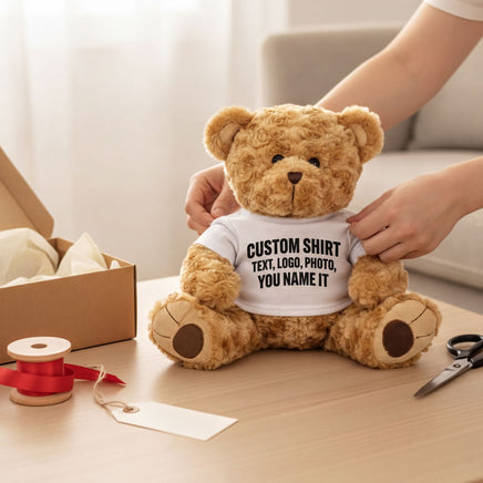 Teddy bear wearing a custom white t-shirt being packed into a gift box with ribbon and a gift tag