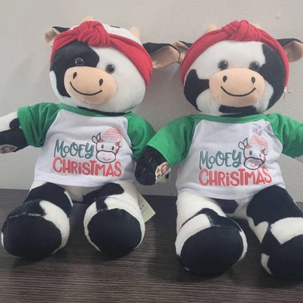 Two stuffed teddy bears sitting next to each other, wearing Christmas-themed shirts and red bandanas.