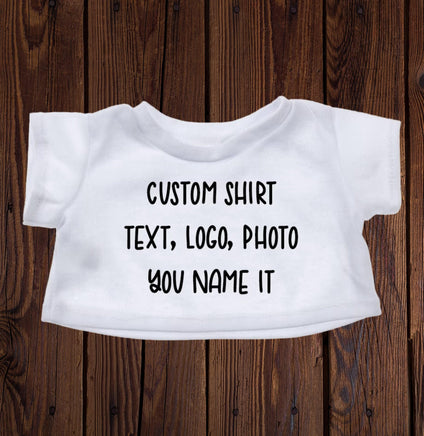 A white t-shirt with custom text printed on it, placed on a wooden surface.