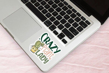 A laptop with a sticker that says "Crazy Plant Lady" on the keyboard.