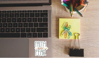a laptop with a keyboard, a yellow sticky note, a binder clip, and a cup of colored pencils on a wooden desk.