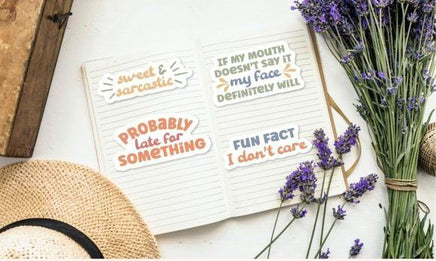 a notebook with various stickers on it, along with a hat, a bunch of lavender flowers, and some other items.