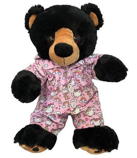 A black teddy bear wearing a pink pajama outfit with unicorn and rainbow patterns.