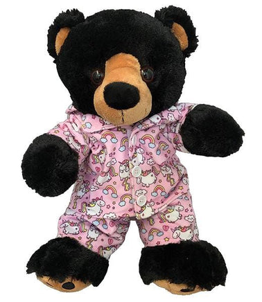 A black teddy bear wearing a pink pajama outfit with unicorn and rainbow patterns.