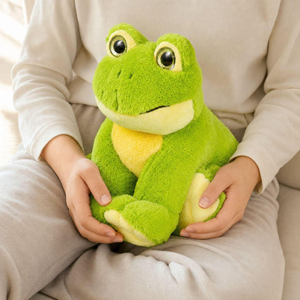 A person is sitting on a couch, holding a green stuffed frog toy.