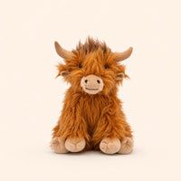 A brown, furry stuffed animal resembling a Highland cow or yak is sitting on a plain background.