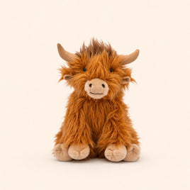 A brown, furry stuffed animal resembling a Highland cow or yak is sitting on a plain background.