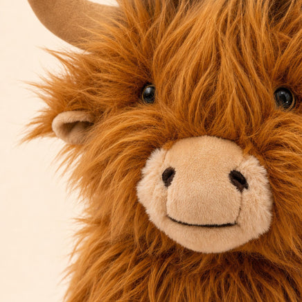 A close-up of a stuffed animal resembling a furry, horned creature with a large, beige nose and a friendly expression.