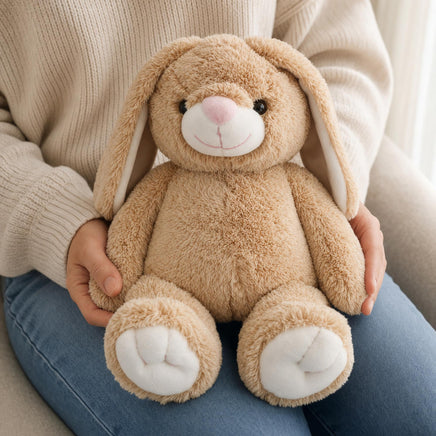 A person is holding a brown stuffed bunny toy in their lap.