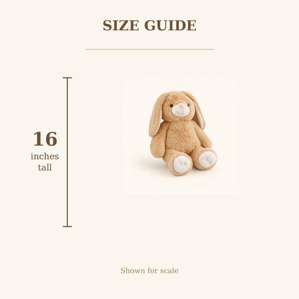a stuffed rabbit toy, likely a plush toy, sitting on a white background. The rabbit appears to be a small, light brown stuffed animal. The image is described as a size guide, which suggests that it provides information about the rabbit's dimensions, such as height and width. The rabbit is shown in a seated position, and the image is described as a "Shown for scale" description, indicating that it is a visual representation of the rabbit's size relative to a standard size chart