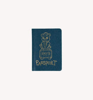 The image is a blue passport cover with a gold illustration of a bear sitting on a suitcase.
