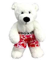 A white teddy bear wearing red and pink patterned boxer shorts with the word "BOXER" printed on them.