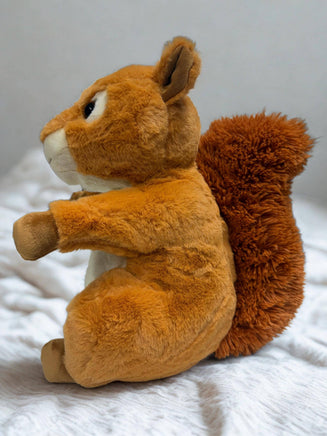 A plush toy of a squirrel sitting on a white surface.