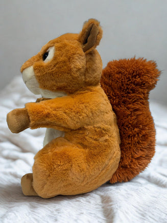 A plush toy of a squirrel sitting on a white surface.