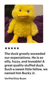 a yellow stuffed duck sitting on top of a bed