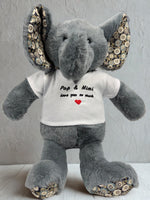 A gray stuffed elephant wearing a white t-shirt with the text "Pop & Mimi love you so much" and a red heart symbol.