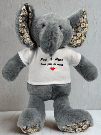 A gray stuffed elephant wearing a white t-shirt with the text "Pop & Mimi love you so much" and a red heart symbol.