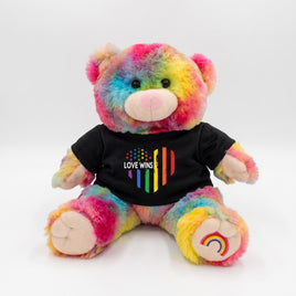 A colorful teddy bear wearing a black t-shirt with a rainbow flag design and the text "LOVE WINS" printed on it.