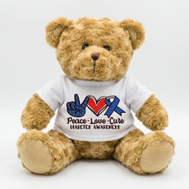 A brown teddy bear wearing a white t-shirt with a peace sign and a blue ribbon symbolizing diabetes awareness.
