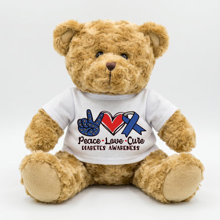 A brown teddy bear wearing a white t-shirt with a peace sign and a blue ribbon symbolizing diabetes awareness.
