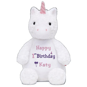 A white stuffed unicorn toy with a pink horn and a personalized birthday message on its belly.