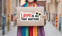 A person wearing a rainbow scarf is holding a sign that says "Love is all that matters".
