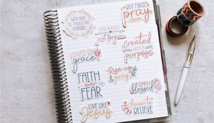 a spiral-bound notebook with various inspirational quotes and phrases written on its pages, along with a pen and some tape.