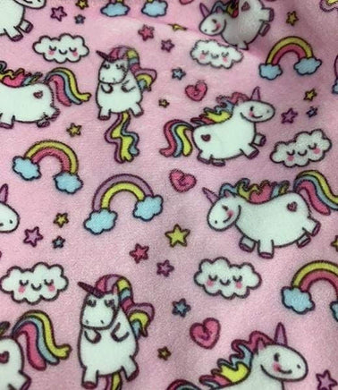 a close-up view of a pink fabric with a repeating pattern of white unicorn illustrations, along with various other whimsical elements such as clouds, rainbows, and stars.