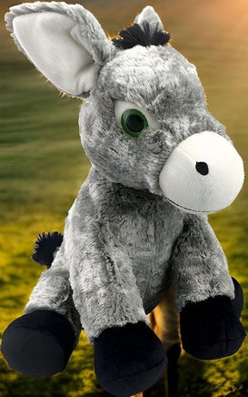 A plush gray donkey toy with black legs and hooves is sitting on a wooden post against a blurred green background.