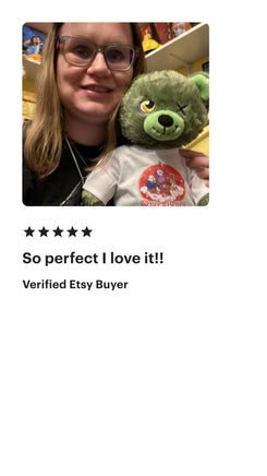 A woman is holding a green teddy bear with a red and white design on its shirt.