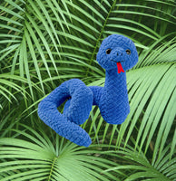 A blue plush snake toy is sitting on top of green palm leaves.