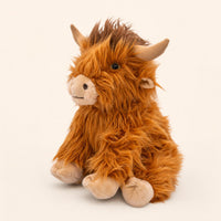 A plush toy of a furry, orange-colored animal with large horns, sitting on a plain background.