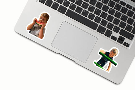 two stickers of children on a laptop keyboard.
