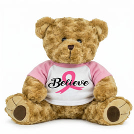 A brown teddy bear wearing a pink shirt with the word "Believe" printed on it.