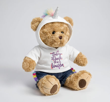 A teddy bear wearing a white hoodie with a unicorn design and a unicorn horn, sitting on a white background.