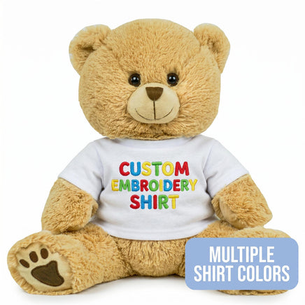 A brown teddy bear wearing a white shirt with colorful text on it.