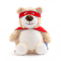 A stuffed teddy bear wearing a red cape and a red bandana, sitting on a white background.