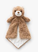 A brown teddy bear with a white face and ears is lying on a white surface.